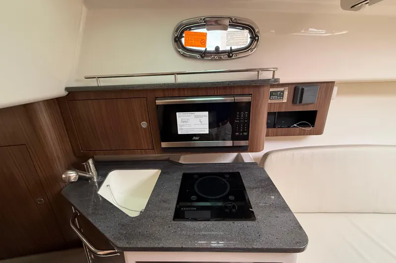 Slide: The Image of 2026 Boston Whaler 285 Conquest interior kitchen with sink, microwave, and stove. - 32