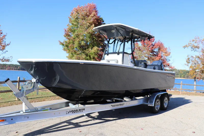 Slide: The Image of 2024 Sea Born LX24 Center Console boat on trailer by a lake in autumn. - 0