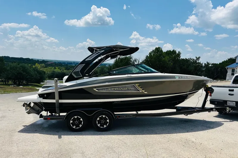 Slide: The Image of 2018 Regal 2300 Bowrider boat on trailer, parked outdoors under a blue sky. - 11