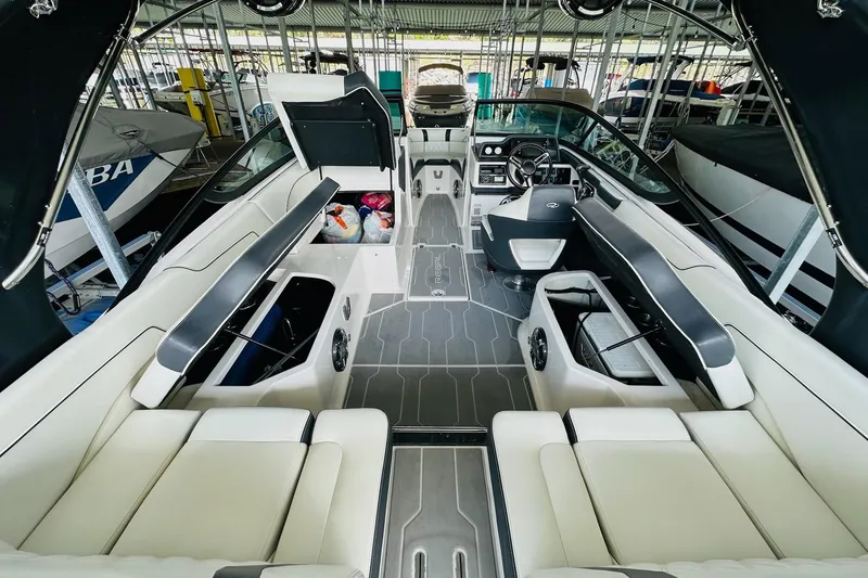 Slide: The Image of 2018 Regal 2300 Bowrider interior with spacious seating and modern dashboard in a marina setting. - 18