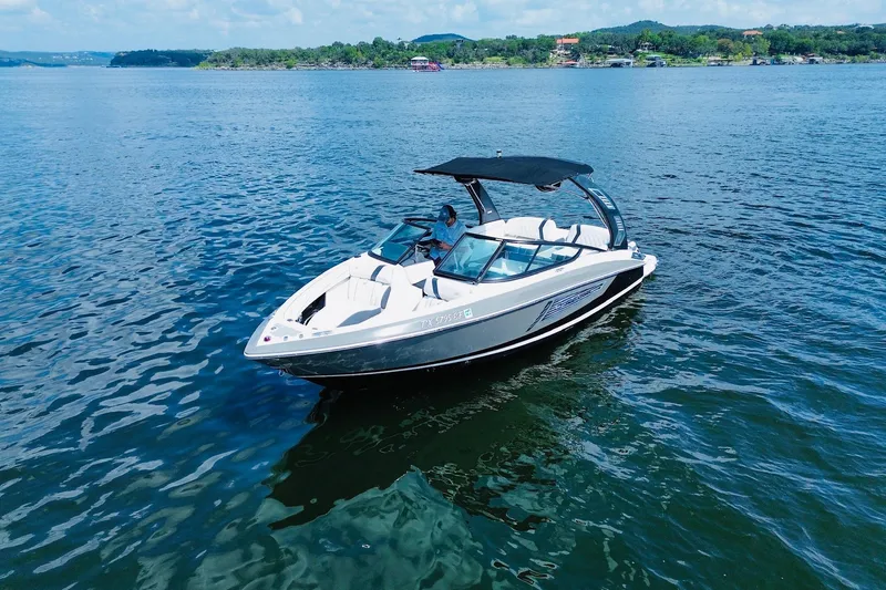 Slide: The Image of 2018 Regal 2300 Bowrider boat on a serene lake with lush green shoreline. - 2