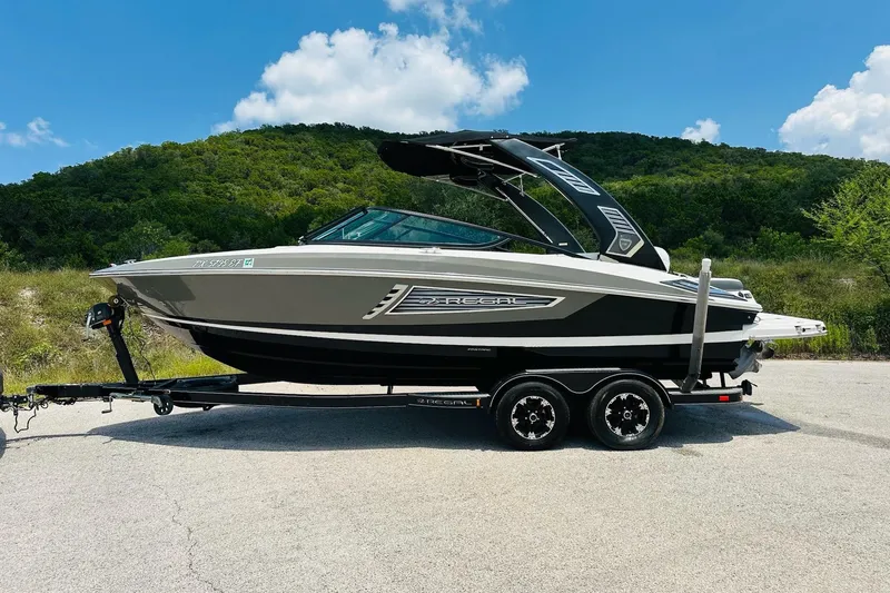 Slide: The Image of 2018 Regal 2300 Bowrider boat on trailer, parked outdoors with scenic background. - 9