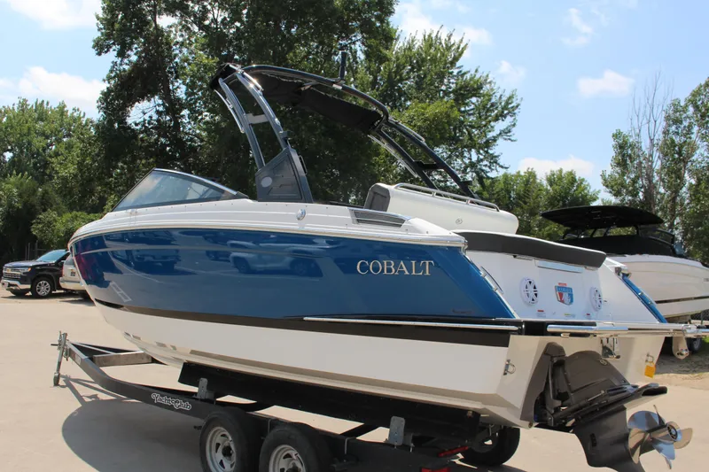 The Image of 2025 Cobalt R4 boat on trailer, blue and white design, parked outdoors. - 1