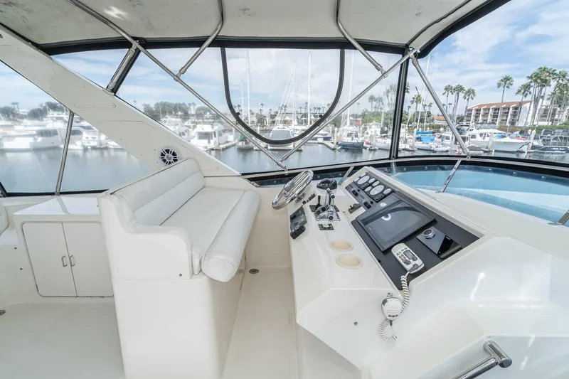 Slide: The Image of 2002 McKinna 57 Pilothouse yacht helm with marina view, featuring modern controls and seating. - 15