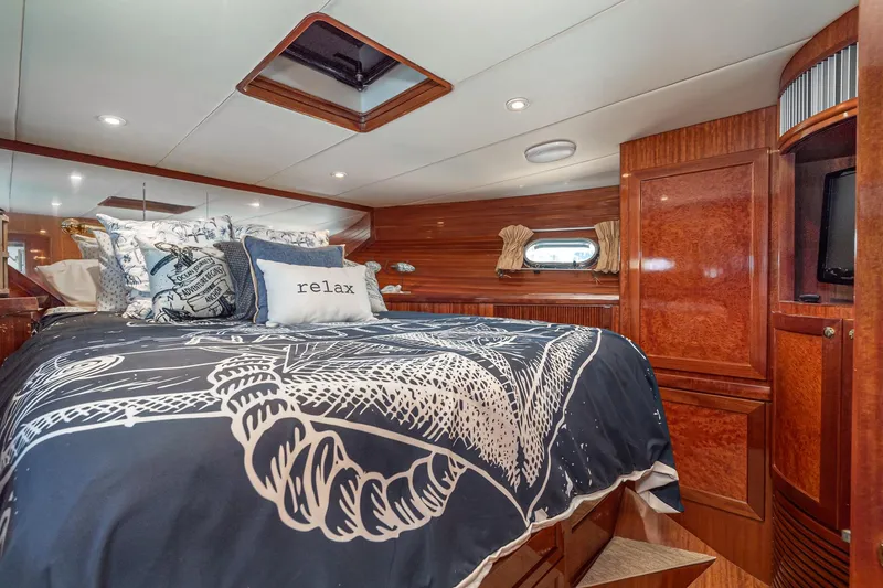 Slide: The Image of Luxurious 2002 McKinna 57 Pilothouse bedroom with elegant wood finish and nautical-themed bedding. - 57