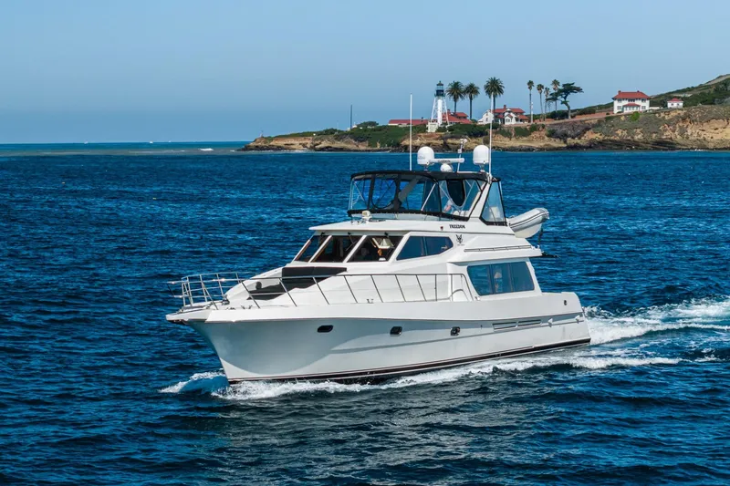 Slide: The Image of 2002 McKinna 57 Pilothouse yacht cruising near a scenic coastal lighthouse. - 6