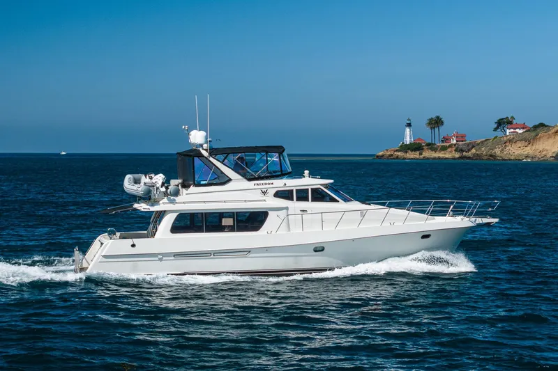 Slide: The Image of 2002 McKinna 57 Pilothouse yacht cruising near a scenic coastal lighthouse. - 7