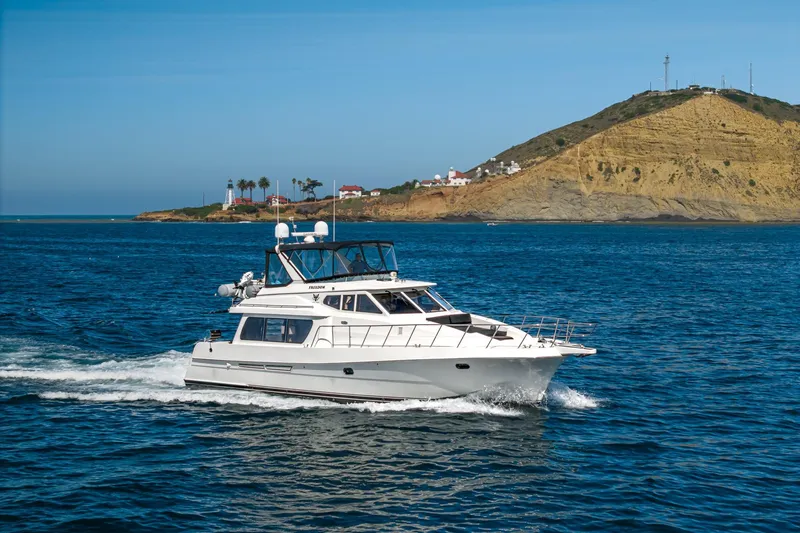 Slide: The Image of 2002 McKinna 57 Pilothouse yacht cruising near a scenic coastal landscape. - 9