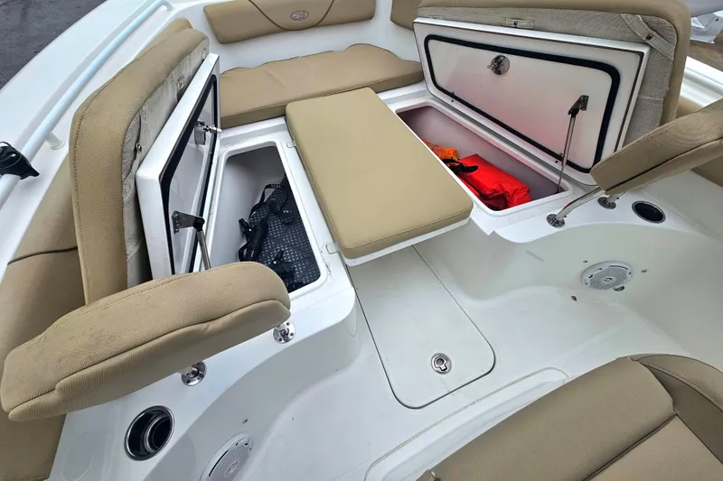 Slide: The Image of 2016 Sea Hunt Gamefish 25 boat interior with open storage compartments and beige seating. - 19
