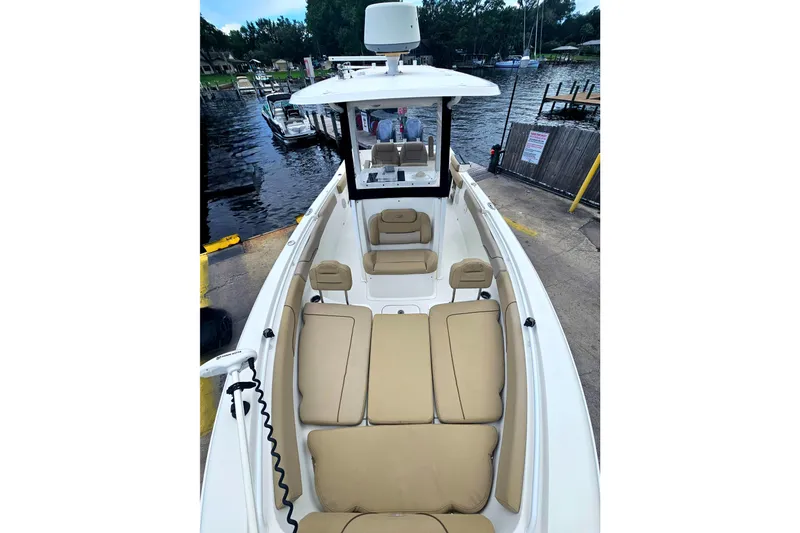 Slide: The Image of 2016 Sea Hunt Gamefish 25 boat with tan seating, docked by a calm waterfront. - 20