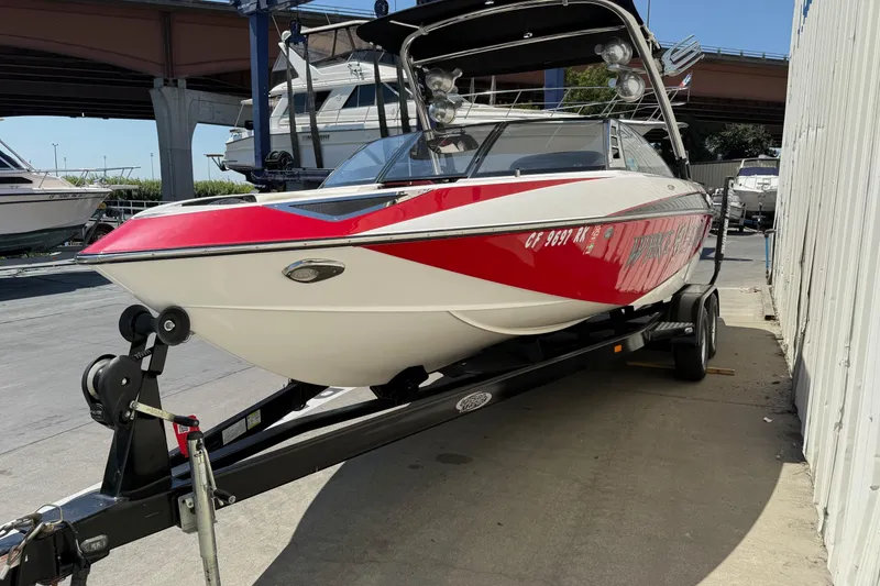 Slide: The Image of 2011 Malibu Wakesetter 23 LSV boat on trailer, red and white design, parked outdoors. - 3