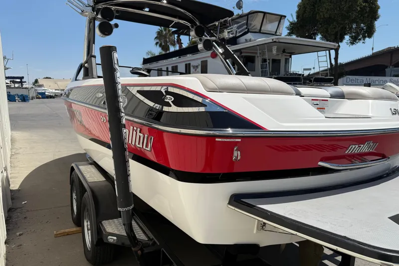 Slide: The Image of 2011 Malibu Wakesetter 23 LSV boat on trailer, red and white design, parked outdoors. - 4
