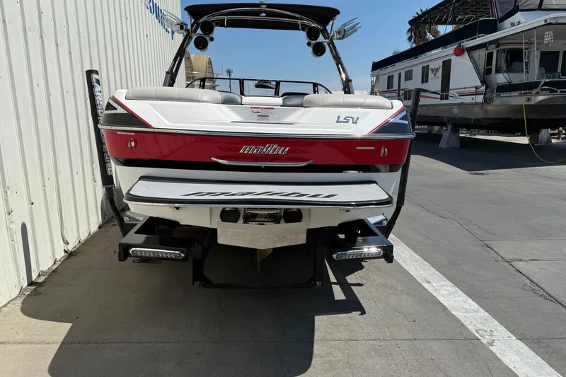 Slide: The Image of 2011 Malibu Wakesetter 23 LSV boat, red and white, docked near a building. - 5