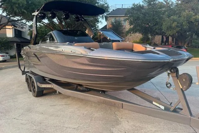 Slide: The Image of 2018 Centurion Fi23 boat on trailer, parked outdoors, with trees and houses in the background. - 10