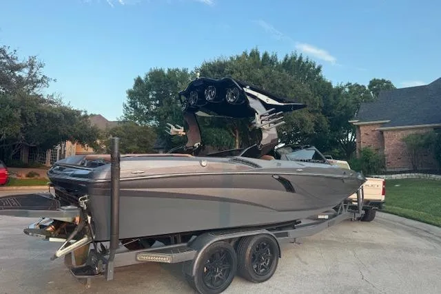 Slide: The Image of 2018 Centurion Fi23 boat on trailer, parked in residential area, with trees and houses in background. - 13