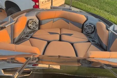 Slide: The Image of 2018 Centurion Fi23 boat interior with tan and gray seating, cup holders, and speakers. - 8