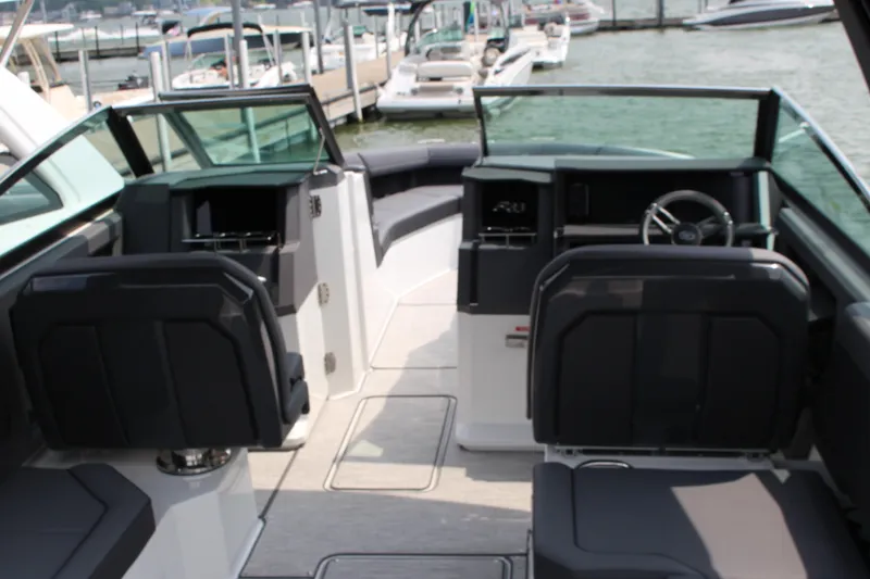 Slide: The Image of 2025 Cobalt R33 boat interior with modern seating and steering, docked at marina. - 3