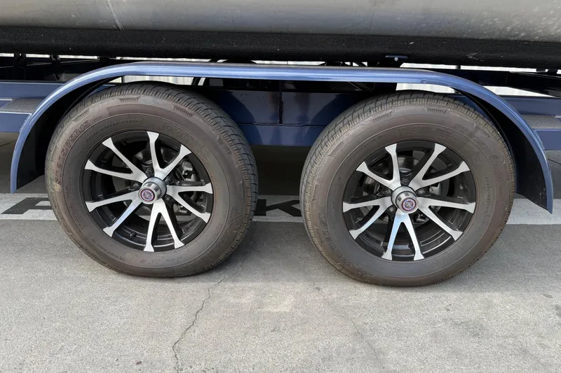 Slide: The Image of Trailer wheels of a 2024 Bennington 23 RSB pontoon boat on pavement. - 28