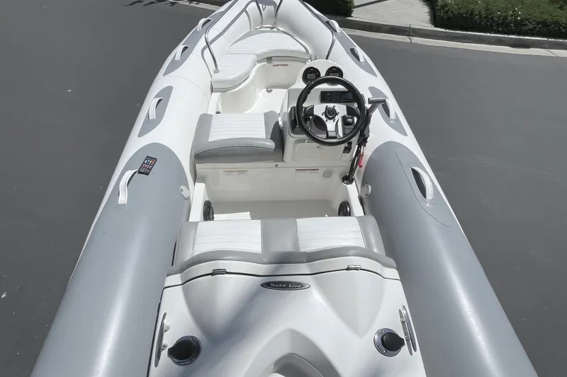 Slide: The Image of 2007 Zodiac Yachtline Deluxe 420 inflatable boat with steering console and seating, parked on pavement. - 16