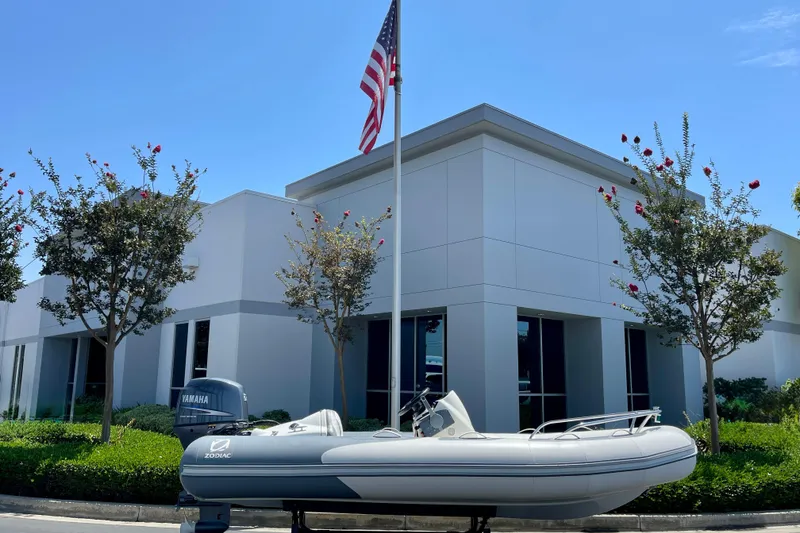 Slide: The Image of 2007 Zodiac Yachtline Deluxe 420 boat displayed outside modern building with American flag. - 2