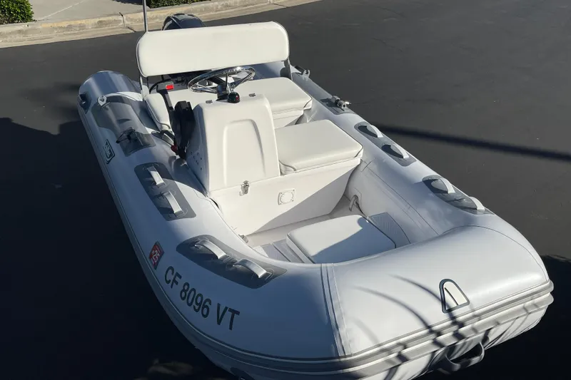 Slide: The Image of 2020 Achilles HB-315DX inflatable boat with steering console, parked on pavement. - 10