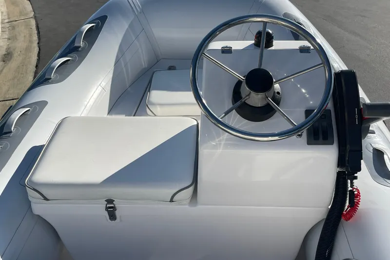 Slide: The Image of 2020 Achilles HB-315DX boat interior with steering wheel and seating. - 2