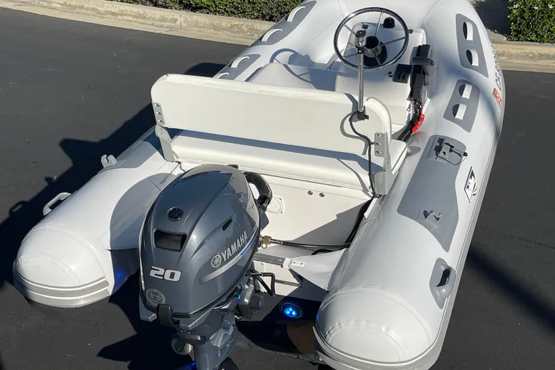 Slide: The Image of 2020 Achilles HB-315DX inflatable boat with Yamaha 20 outboard motor, parked on pavement. - 9