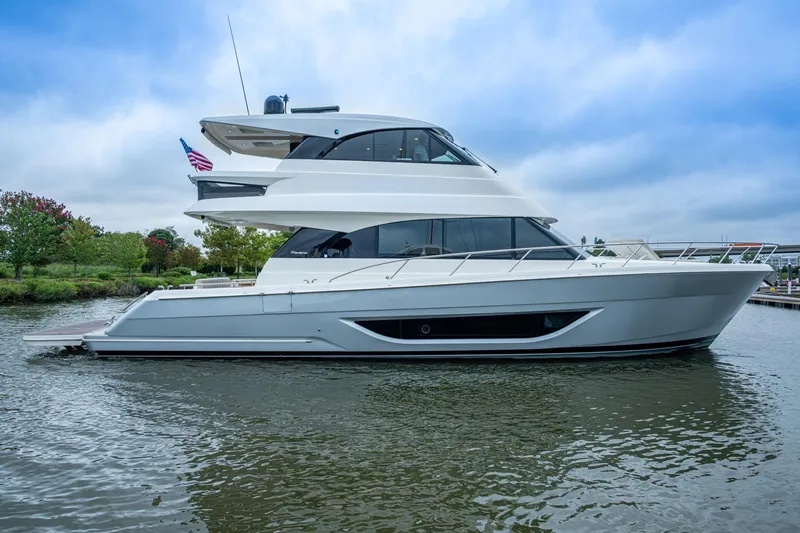 Slide: The Image of 2023 Maritimo M55 yacht on water, sleek design, American flag, cloudy sky. - 113