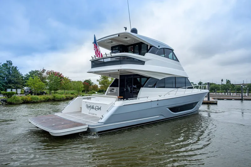 Slide: The Image of 2023 Maritimo M55 yacht on water, rear view with American flag, lush greenery background. - 117