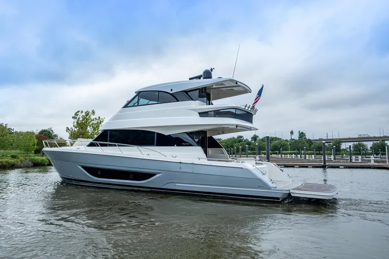 Slide: The Image of 2023 Maritimo M55 yacht docked on a calm river under a cloudy sky. - 122
