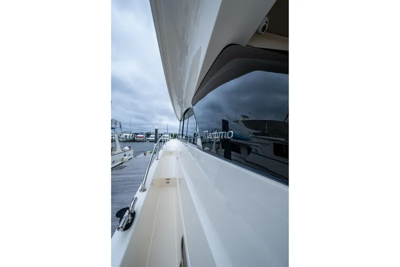 Slide: The Image of 2023 Maritimo M55 yacht side view at marina, showcasing sleek design and reflective windows. - 15