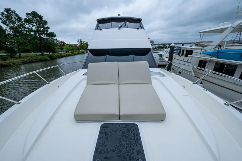 Slide: The Image of 2023 Maritimo M55 yacht with cushioned deck seating, docked by a scenic waterway. - 18