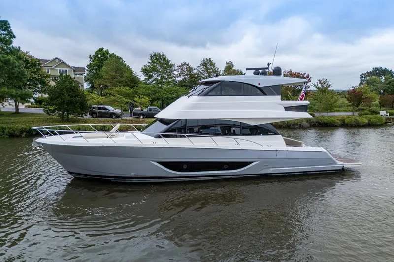 Slide: The Image of 2023 Maritimo M55 yacht on a serene river with lush greenery. - 2