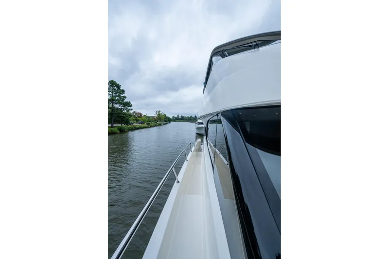 Slide: The Image of 2023 Maritimo M55 yacht cruising on a serene river under cloudy skies. - 20