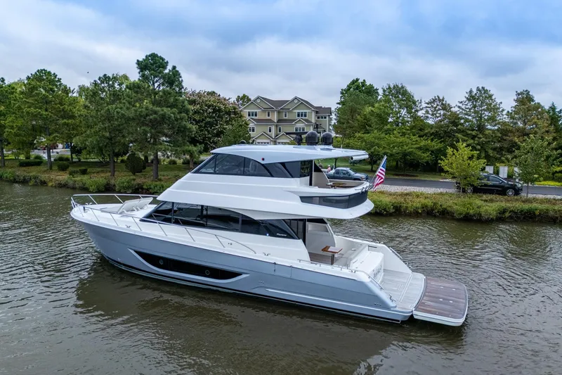 Slide: The Image of 2023 Maritimo M55 yacht cruising on a serene river with lush greenery. - 3