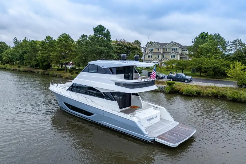 Slide: The Image of 2023 Maritimo M55 yacht cruising on a serene river near lush greenery and houses. - 4