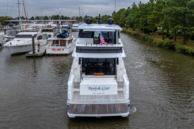 Slide: The Image of 2023 Maritimo M55 yacht cruising in a marina, surrounded by other boats and lush greenery. - 6