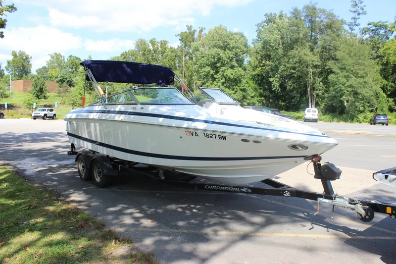 The Image of 2006 Cobalt 246 boat on trailer in parking lot, surrounded by trees. - 0