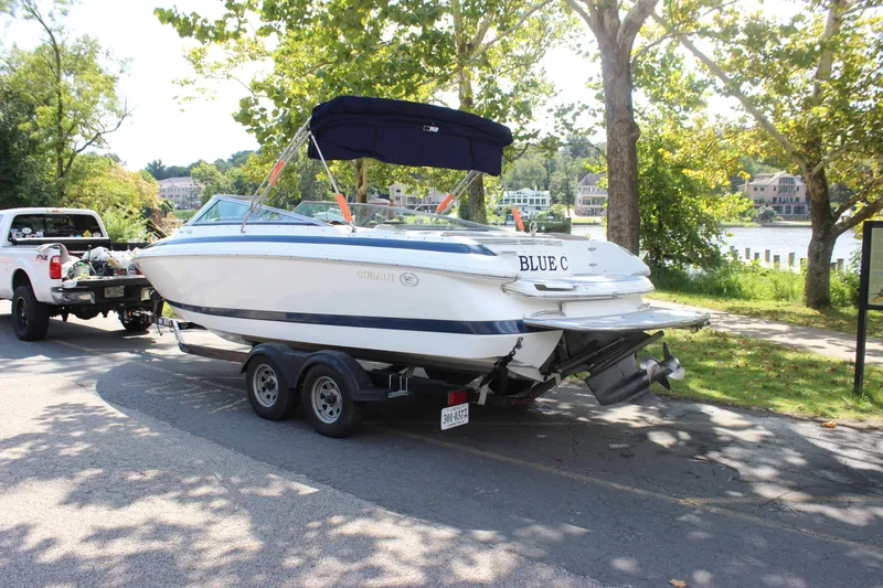 Slide: The Image of 2006 Cobalt 246 boat on trailer, parked near a scenic lakeside area. - 15