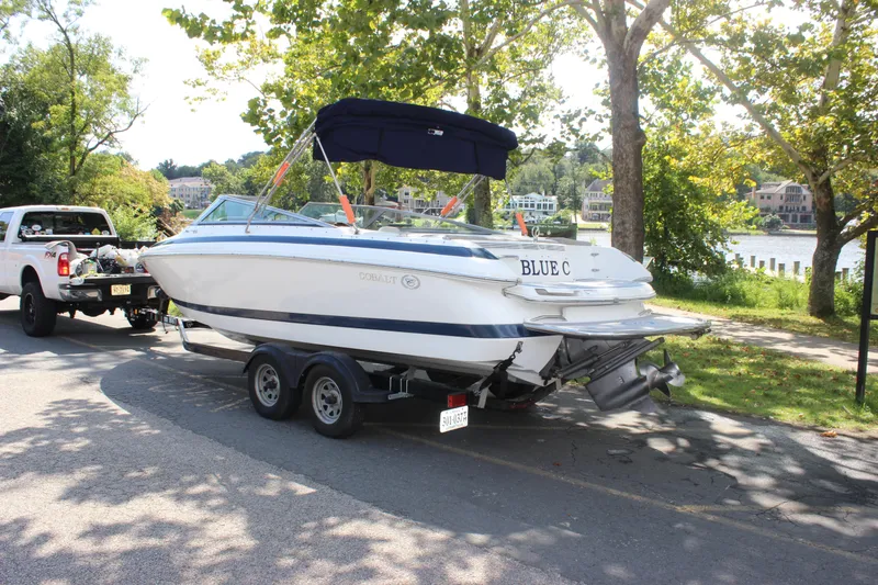 Slide: The Image of 2006 Cobalt 246 boat on trailer, parked near a scenic lakeside area. - 16