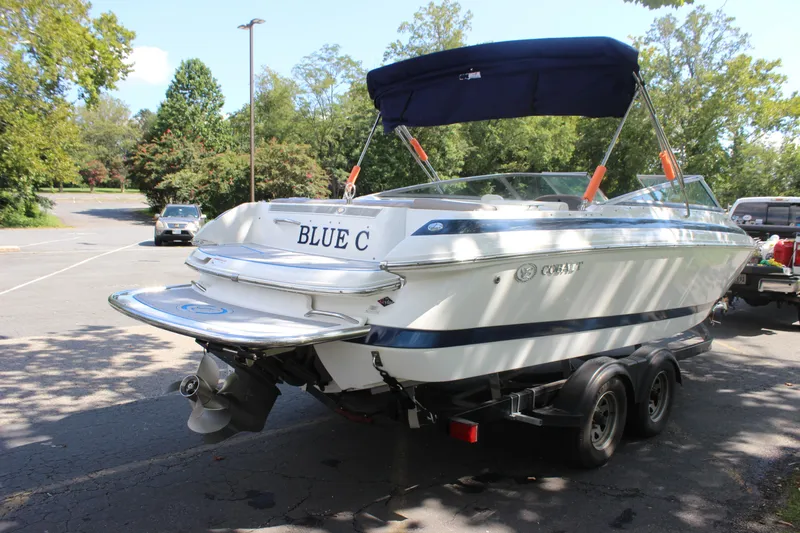 Slide: The Image of 2006 Cobalt 246 boat on trailer in a parking lot, surrounded by trees. - 18