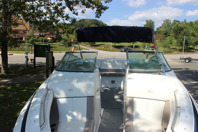 Slide: The Image of 2006 Cobalt 246 boat with open seating and canopy in a scenic park setting. - 23