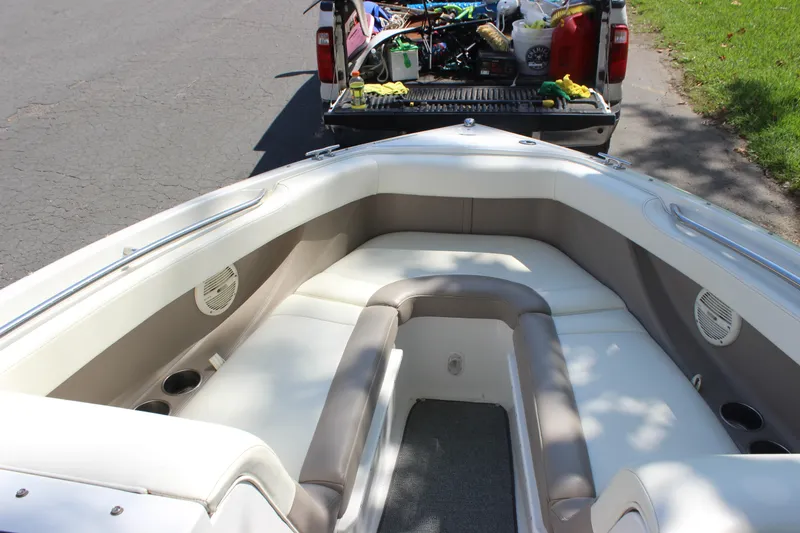 Slide: The Image of 2006 Cobalt 246 boat interior with seating, parked near a truck loaded with gear. - 7