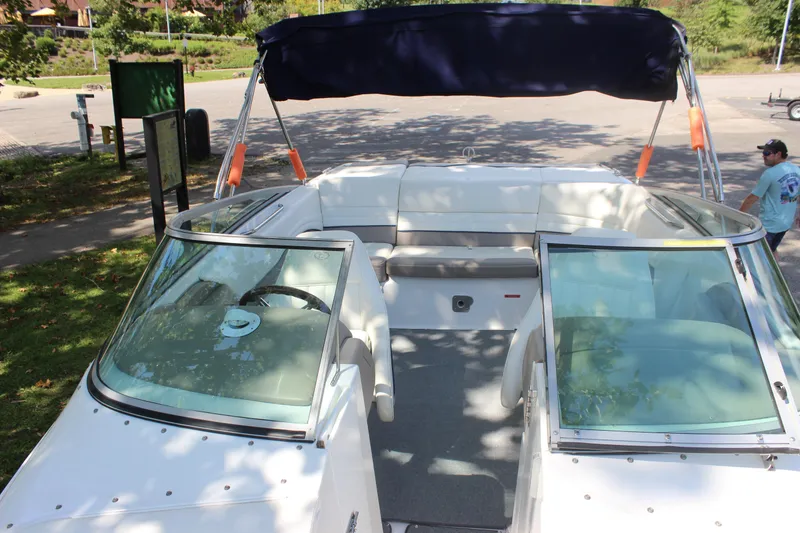 Slide: The Image of 2006 Cobalt 246 boat with open deck and canopy in a sunny park setting. - 9