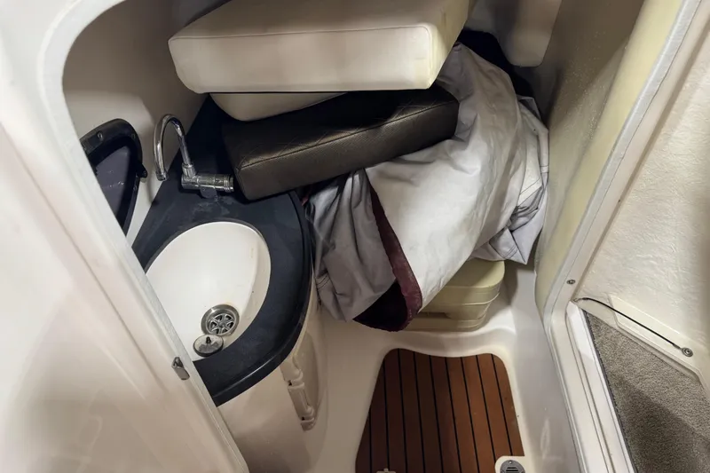 Slide: The Image of 2012 Regal 2700 Bowrider interior with sink, cushions, and wooden flooring. - 14