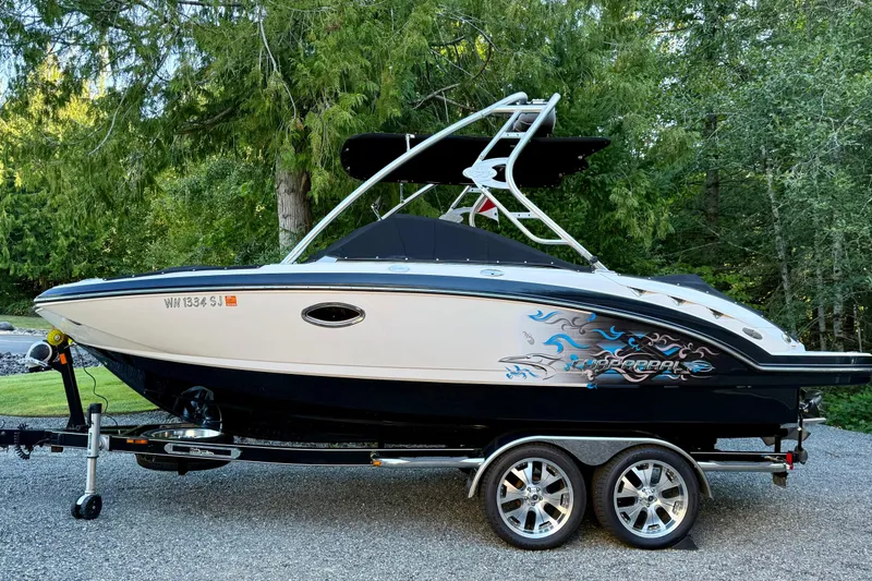 Slide: The Image of 2009 Chaparral Sunesta 224 Xtreme boat on trailer, surrounded by lush greenery. - 0