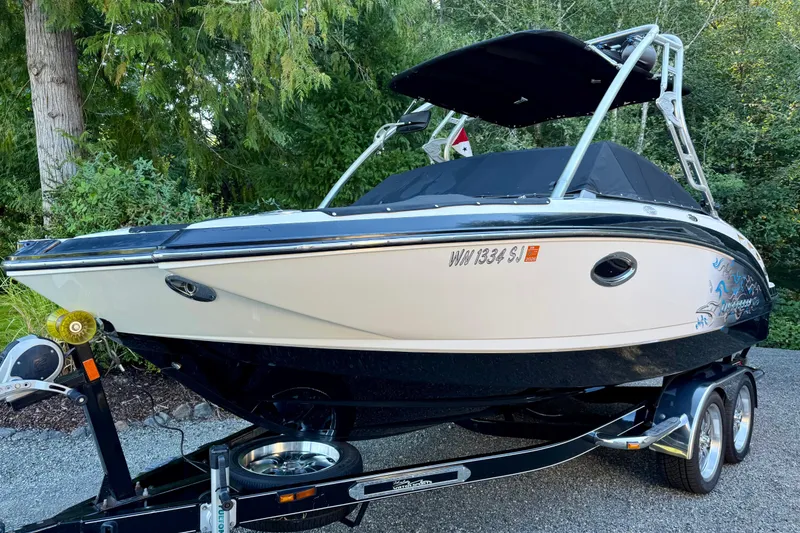 Slide: The Image of 2009 Chaparral Sunesta 224 Xtreme boat on trailer, surrounded by lush greenery. - 1