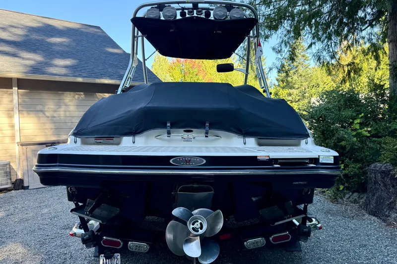 Slide: The Image of 2009 Chaparral Sunesta 224 Xtreme boat, rear view, covered, parked on gravel driveway. - 12