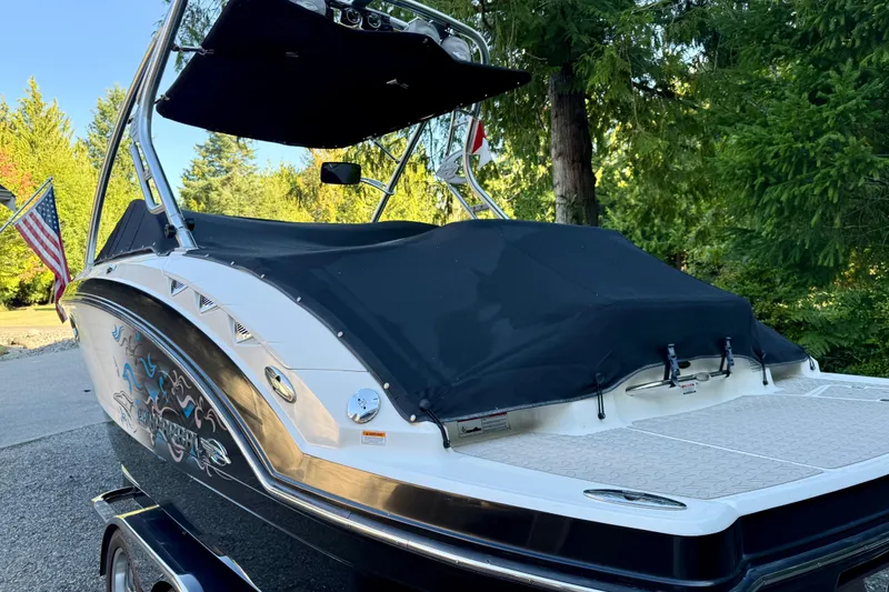 Slide: The Image of 2009 Chaparral Sunesta 224 Xtreme boat with cover, parked outdoors near trees. - 13