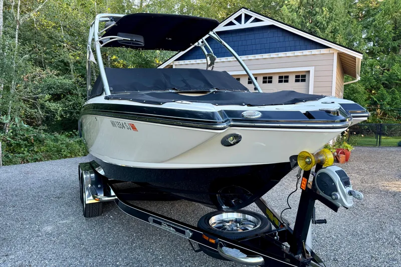 Slide: The Image of 2009 Chaparral Sunesta 224 Xtreme boat on trailer, parked near a garage. - 2
